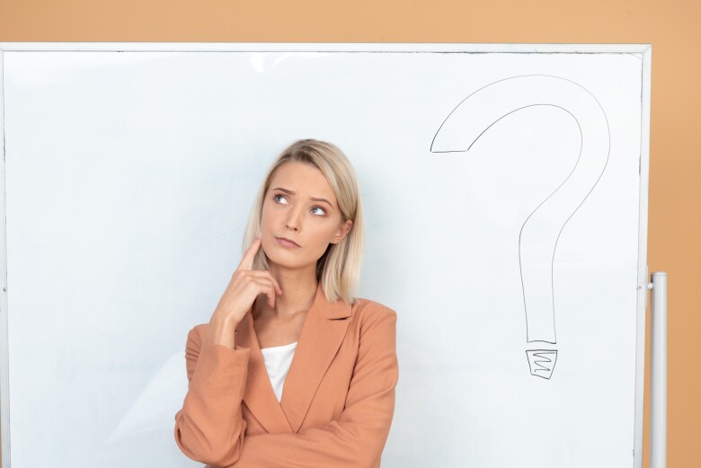 pensive-young-teacher-standing-next-to-a-whiteboard-with-question-mark-on-it